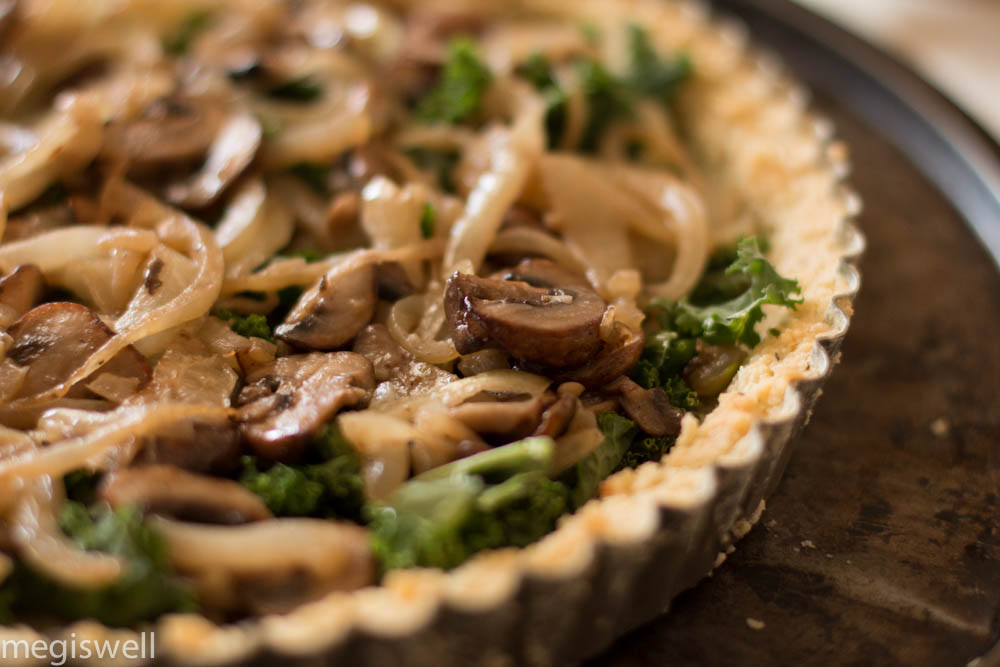 Sautéed mushrooms, onions, and French cream make this Kale, Onion, and Mushroom Quiche creamy while the kale adds a slight crunch and a crumbly almond flour crust melts in your mouth. Perfect for breakfast, brunch, lunch, and dinner! | www.megiswell.com 