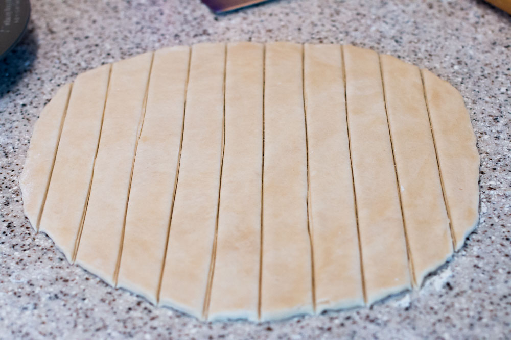 Rolled out pie dough cut into equal sized strips for the woven crust.