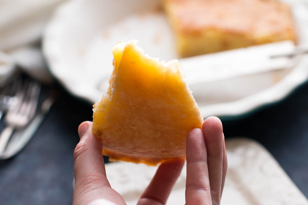 Shot of a hand showing off the bottom of a slice of lemon chess pie.