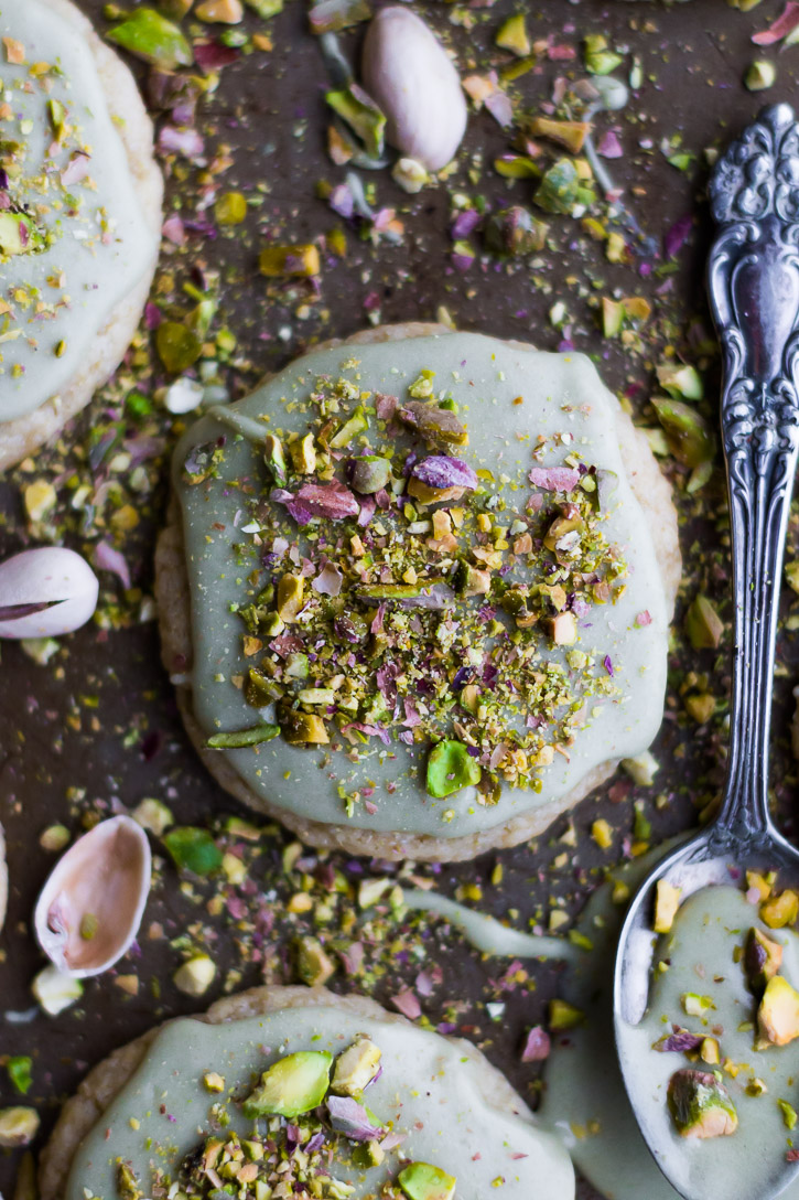 Close up overhead shot of pistachio covered cookie next to a spoon covered with frosting.