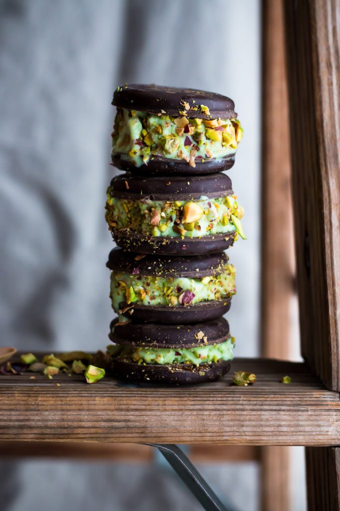 Vertical side shot of 4 pistachio ice cream sandwiches stacked on top of each other.
