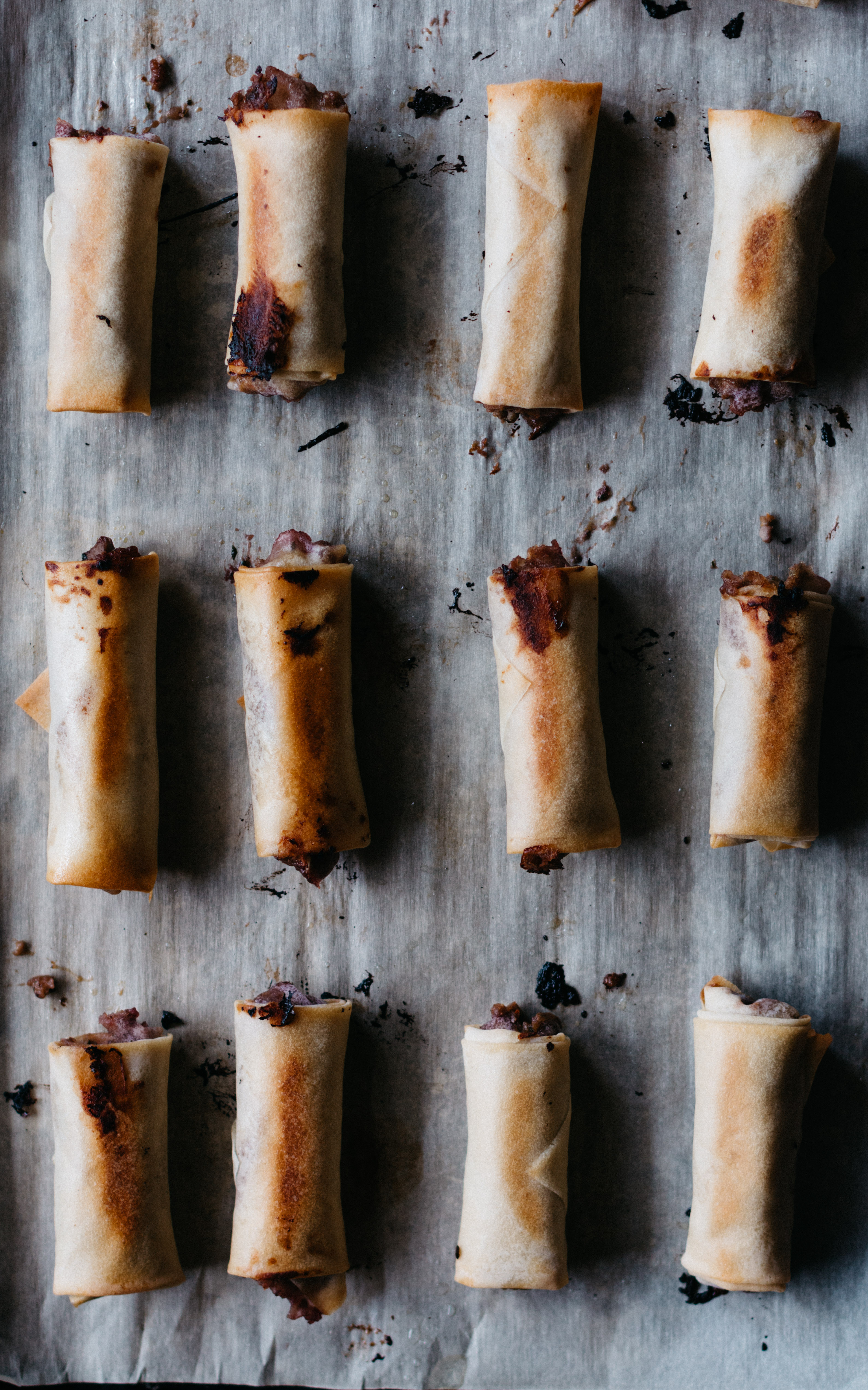 rows of baked Duck Spring Rolls laid out on a parchment covered baking sheet