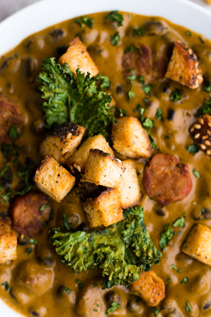 A close up of the croutons and kale chips in the Creamy Red Pepper and Andouille Sausage Soup