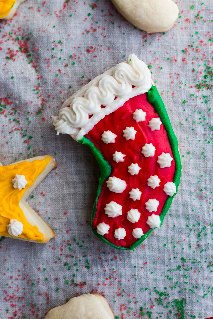 Frosted cookie shaped like a Christmas stocking on a sprinkle covered clothe back ground.