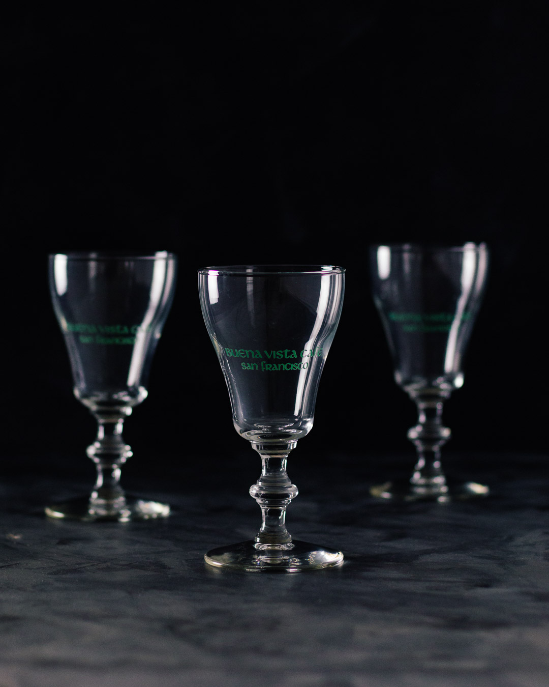 Vertical side shot of three Buena Vista Irish Coffee goblet glasses.