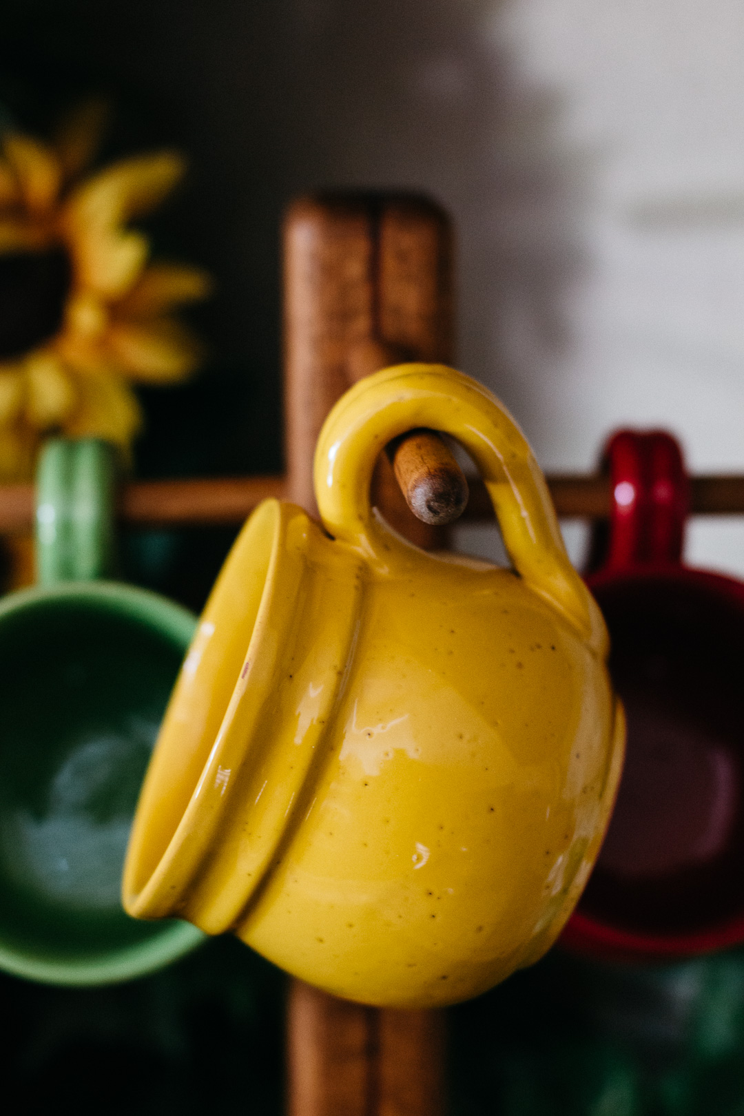 A close up of a ceramic mug hanging from a wooden mug rack.