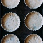 Overhead shot of 6 tart pans with uncooked crust in them.