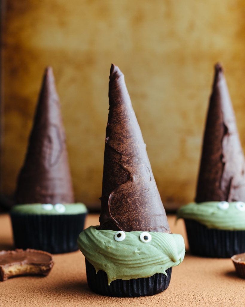 These chocolate Reese’s Peanut Butter Cup Cupcakes have a secret peanut butter cup treat at the bottom and Reese’s frosting. Decorated like witches, they are the perfect Halloween trick AND treat. #halloween #halloweencupcakes #partyrecipes #reeses #peanutbutter #chocolatecupcakes #reesescupcakes | www.megiswell.com