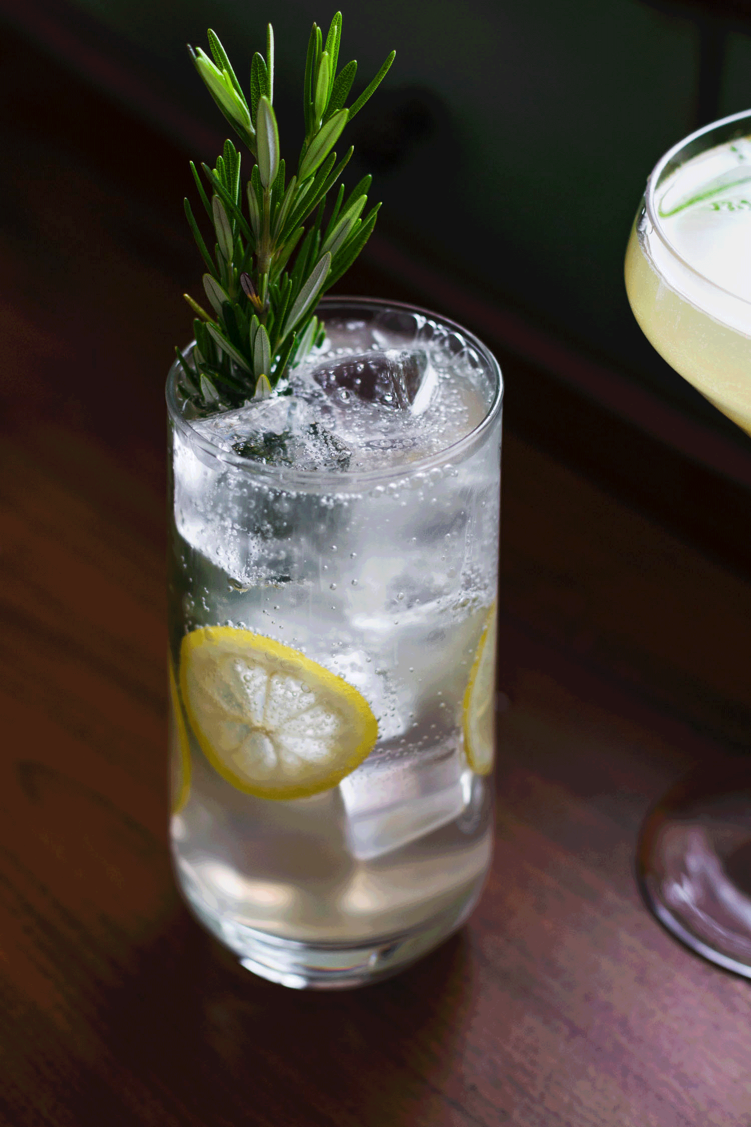 Gif of fizzing Gin Lemonade Cocktail in a highball glass with lemon slices and a sprig of rosemary.